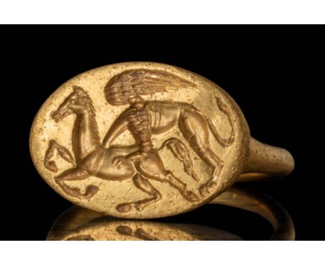 Ca. 450 - 300 BC.
A stunning gold ring with a tubular section round hoop connected to the bottom of an oval bezel engraved wi