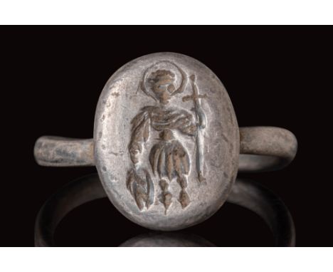 Ca. AD 500 - 800.
A silver ring with a tubular section round hoop connected to a round bezel. The bezel is engraved with a st