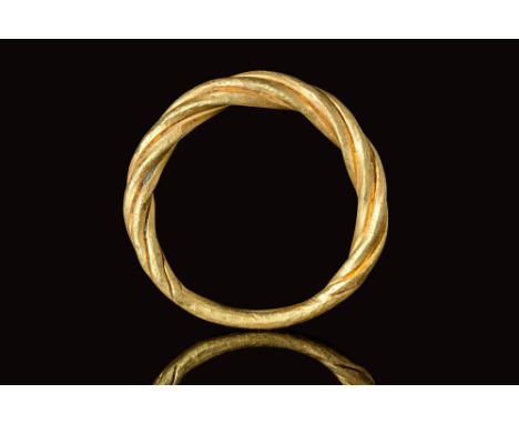 Ca. AD 800 - 1100.An elegant solid gold ring with a round hoop formed from four intertwined strands, tapering into a thinner,