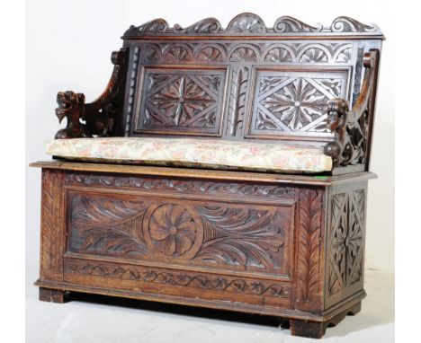 A late 19th century Victorian carved oak hall settle bench. The bench with dragon carved elbow rests / arms having a hinged s