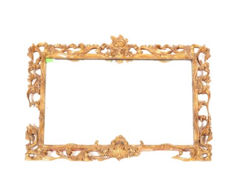 A vintage 20th Century giltwood wall hanging mirror having ornate foliate and scrolled open frame housing a central mirrored 