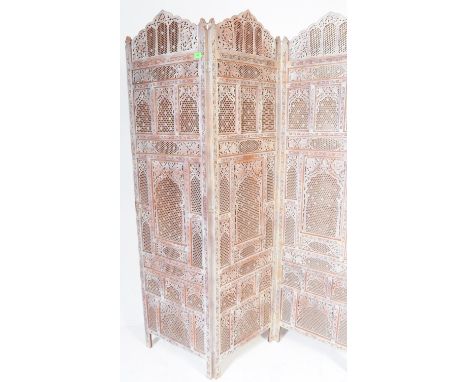 A 20th century carved hardwood Moroccan four fold discretion - panel dressing screen. Arched tops with carved and detailed up