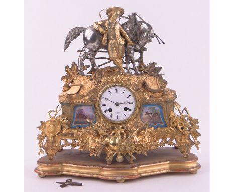 An ornate 19th century French gilt metal cased mantle clock,surmounted by a figure and horse with inset painted porcelain pan