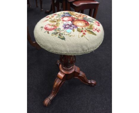 A rise and fall decorative piano stool with tapestry top resting on centre support to heavily carved legs and tripod base.