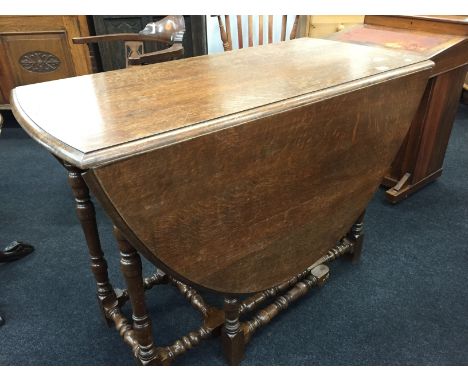 A large oak gate-leg table resting on turned supports.