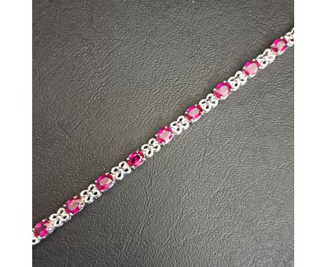 RUBY SET LINE BRACELETthe fourteen oval cut rubies separated by shaped and pierced links, each of the rubies approximately 0.