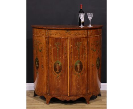 A Sheraton Revival satinwood and painted demilune side cabinet, slightly oversailing top painted with a ribbon-tied oval rese