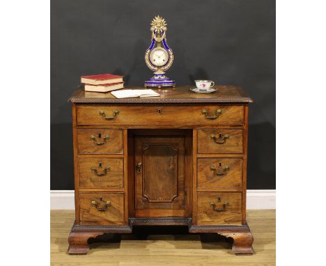 A George III mahogany kneehole desk, rectangular top with moulded foliate carved edge centred by a four-pointed star, above a