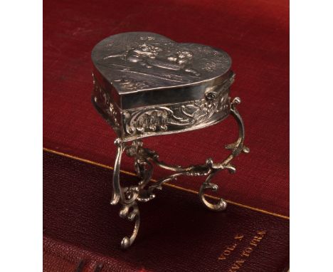 A Continental silver novelty trinket box, as a heart shaped table, embossed with putti, scroll legs, gilt interior, 6cm high,