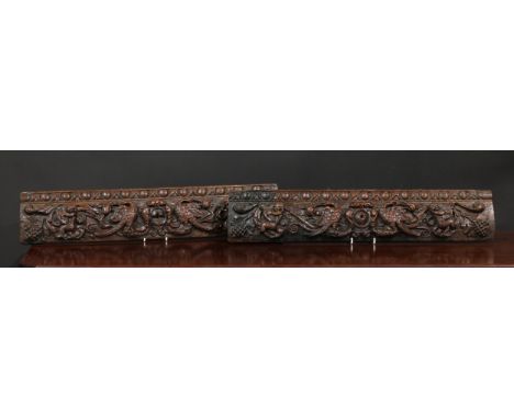 A pair of 17th century oak rectangular panels, each carved with birds, fruiting foliage and putti playing musical instruments