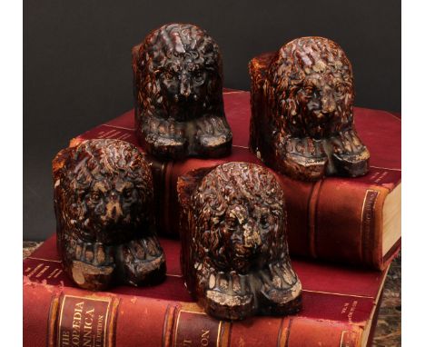 A set of four 19th century Staffordshire treacle glazed sash window stops or furniture rests, each modelled as a lion, 15cm d