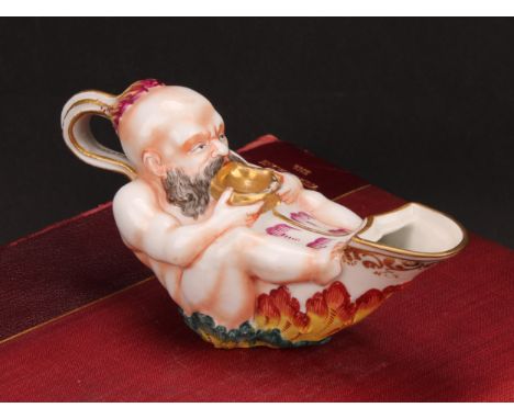 A Naples porcelain inkwell, shaped as an oil lamp, moulded with a Bacchanalian reveller, painted in polychrome, 15cm long, 19