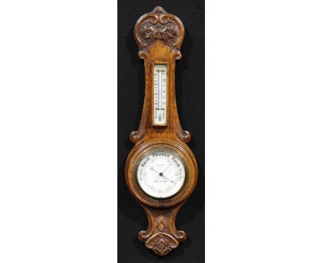 A late Victorian/Edwardian oak wheel barometer, 11.5cm circular register inscribed W.H. MAY, NOTTINGHAM., the case carved wit