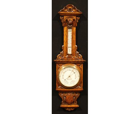 A late Victorian oak barometer, 18.5cm circular register inscribed FINNIGANS LTD, MANCHESTER, the case carved and applied wit