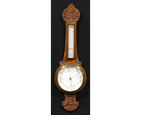 An early 20th century oak wheel barometer, 18.5cm circular register, the case carved with an anthemion-like arrangement of st