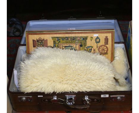 A good quality suitcase and contents of two sheepskins and a painted wooden plaque bearing the signature R F Harnet along wit