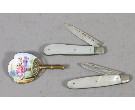 Two Victorian silver folding fruit knives with mother of pearl scales along with a brass and enamel brooch formed as a fan.