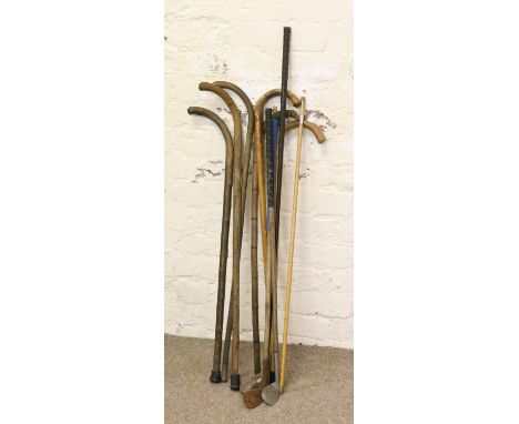 A collection of old walking sticks and golf clubs along with a yard stick.