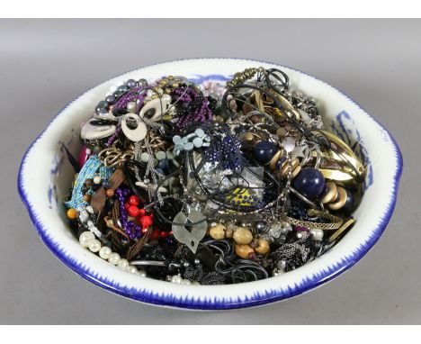 A blue and white wash basin containing a large quantity of costume jewellery to include beads, bangles, necklaces etc.