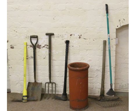 A terracotta chimney pot and collection of gardening tools.