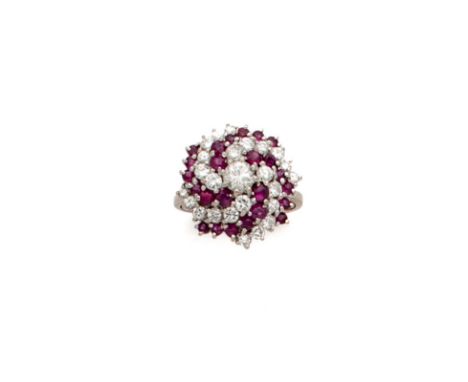 RUBY AND DIAMOND DRESS RING, 1960s, the brilliant-cut diamond bouton cluster decorated with curving rows of circular rubies o