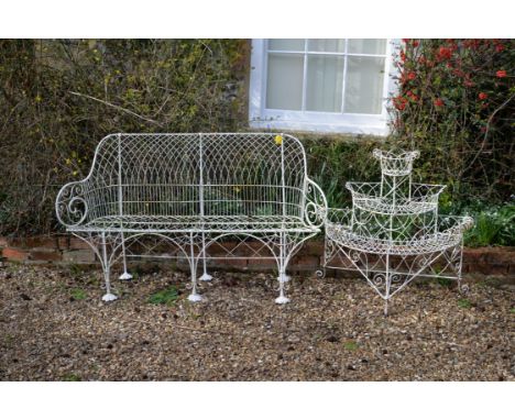 A white painted wrought metal garden seat, early 20th century, in the manner of Regency wirework, the openwork frame with twi