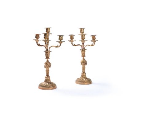 A pair of French gilt metal four light convertible candlesticks in Louis XVI taste, late 19th/early 20th century, the foliate