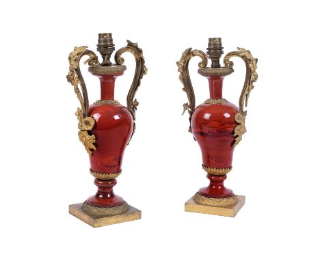 A pair of French gilt metal and red glazed ceramic urn table lamps, first half 20th century, each with foliate cast scrolled 