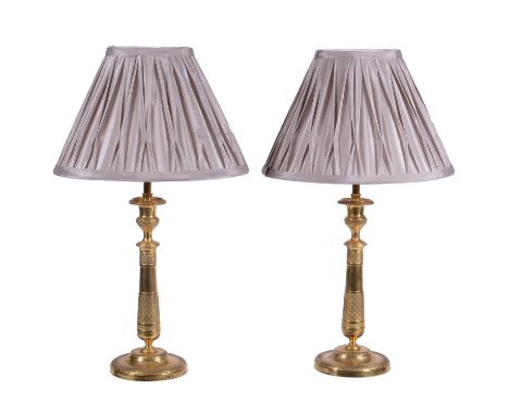 A pair of French gilt metal candlesticks in Empire style, refitted as lamps, the electrical fitments rising from urn form noz