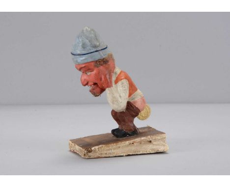 A mid 19th century Thüringen Dukatenscheißer man ‘shitting’ money squeak toy, the composition man with blue cloth hat, red fa