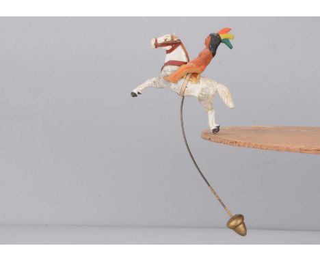 An early 20th century composition Native American balancing toy, the brave with feathers headdress riding a white painted gal