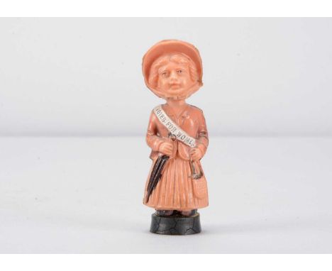 A late 19th century or early 20th century German celluloid Suffragette,  with moulded bonnet, ‘Votes for Women’ sash, holding