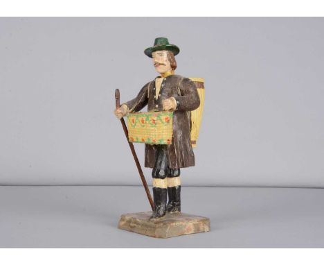 An 19th century German carved wooden man pedlar,  with nodding head, painted brown hair and moustache, green painted hat, lon