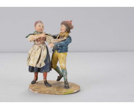 A mid 19th century Rhöner carved wooden group of two children dancing,  the boy with fur trimmed hat, flowing hair and yellow