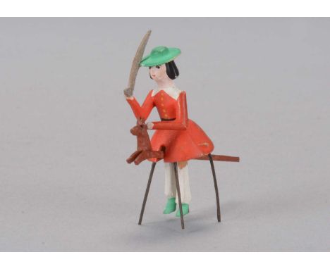 A late 19th century German bristle toy of a boy riding a hobbyhorse,  wooden with composition head, green painted hat and sho