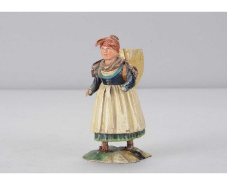 A mid 19th century Rhöner carved wooden woman walking with wicker basket on back, In traditional dress with red head scarf, c