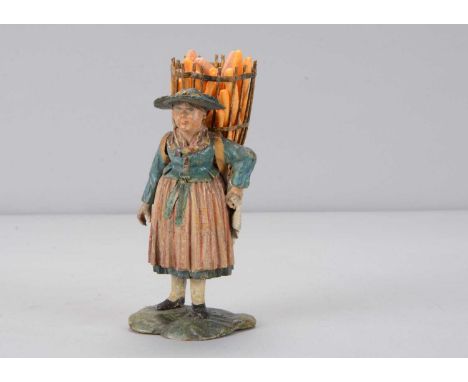 A mid 19th century Rhöner carved wooden girl heading to market, traditionally dressed with wide brimmed hat, colourful scarf,