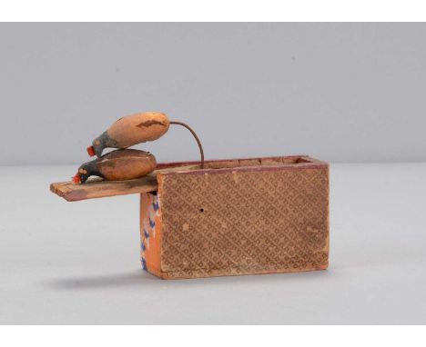 A mid 19th century Erzgebirge chicken toy, a paper covered wooden box with sliding lid with hen, when the lid is slid a cock 