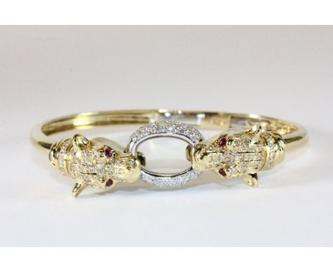 An 18ct gold Cartier style diamond and ruby set panther bangle. Est. £1,200 - £1,400