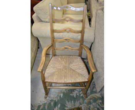 An oak country rocking chair, shaped and pierced ladder back, raffia seat