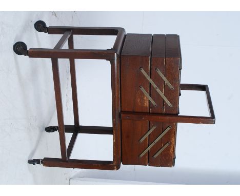 A vintage 1950's retro metamorphic sewing box raised on stand. The box with hinged sections, handles to centre. Measures: 75 