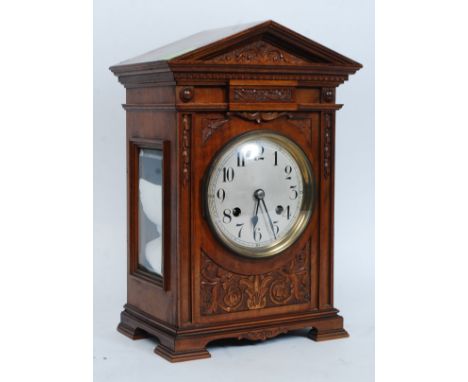 An oak cased eight day mantle clock, enamel dial with Arabic numerals, on a German brass twin barrel movement striking on two