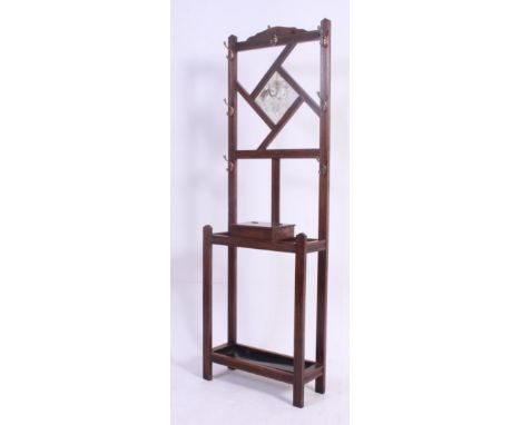 An Edwardian mahogany hall stand having mirror upright with hooks and a central glove box over drip tray stick stand base. Me