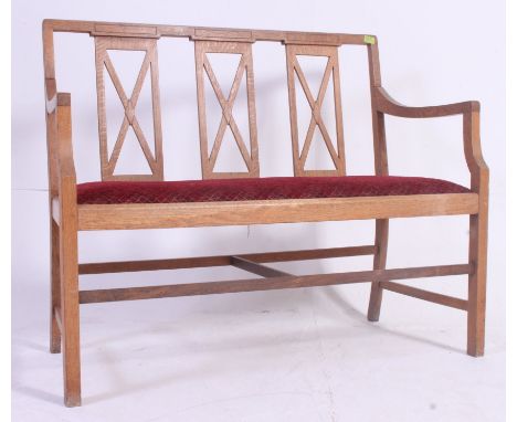 An Edwardian Arts & Crafts hall settle bench. Made of solid oak having an organic simple form with shaped elbow rests, railed