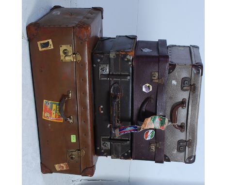 A stack of vintage 20th century suitcases to include a large leather example with applied vintage shipping labels. Along with