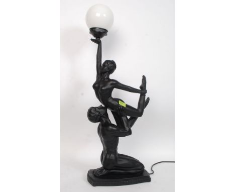 A contemporary Art Deco style figural lamp in the form of a man and lady held aloft. Complete with circular globe to top. H83