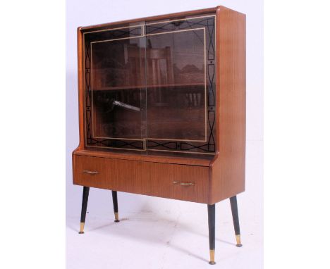 A compact vintage mid 20th century  drinks cocktail cabinet having detailed sliding glass doors over lower drawer all being r