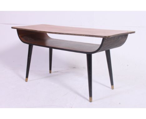 A 1970's teak and ebonised surfboard style retro coffee table. Raised on ebonised dansette style legs with shaped magazine sh