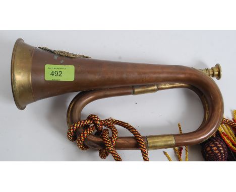 A believed 19th cenutry brass mounted copper military bugle horn being applied with the badge of the Argyll and Sutherland Hi
