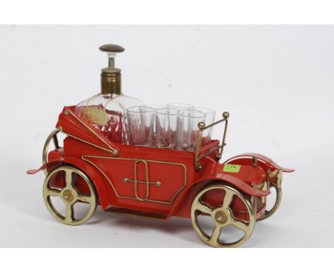 A vintage 1970's Decanter in the shape of a car with glasses to front. Brass wheels, of metal construction 